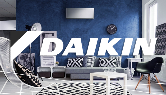 Klimaanlage von Daikin an dunkelblauer Wand in Wohnzimmer oberhalb von grauer Couch mit Logo Schriftzug