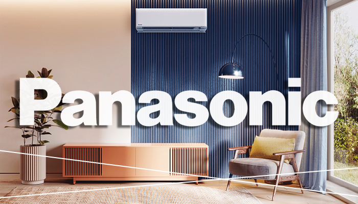 Klimaanlage von Panasonic neben Verandatüre und oberhalb einer bauchigen Lampe und einer Kommode aus Holz mit Logo Schriftzug
